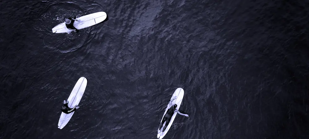 Vue aérienne de surfeurs attendant la vague, symbolisant la préparation stratégique et le dialogue